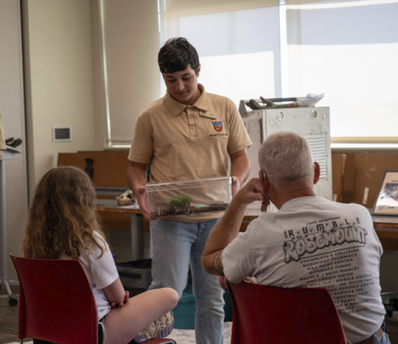zoo keeper showing people a box with a reptile