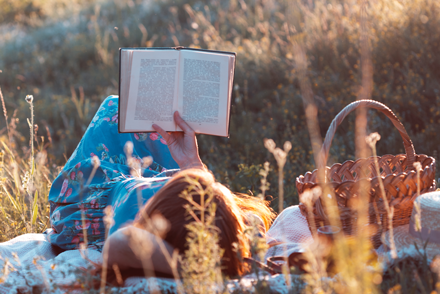 woman in grassy field reading